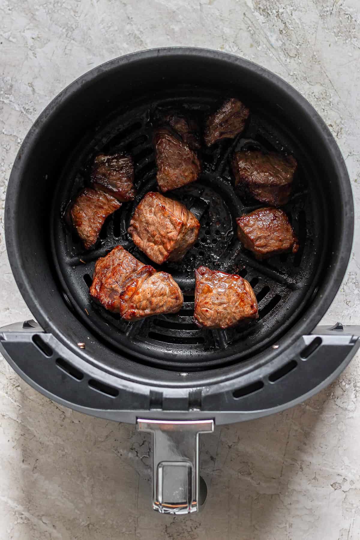 Chunks of cooked meat resting in an air fryer basket.