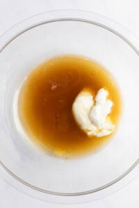 A glass bowl containing a mixture of liquid honey and a dollop of yogurt.