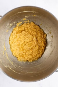 A metal bowl containing a yellow mixture is shown from above.