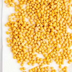 A large number of yellow chickpeas spread out on a white paper towel.