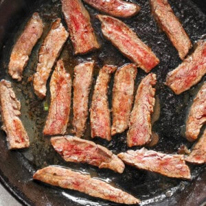 Slices of cooked meat in a black skillet.