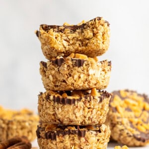 A stack of four granola clusters with visible chocolate coating and peanut toppings, arranged on a light background.