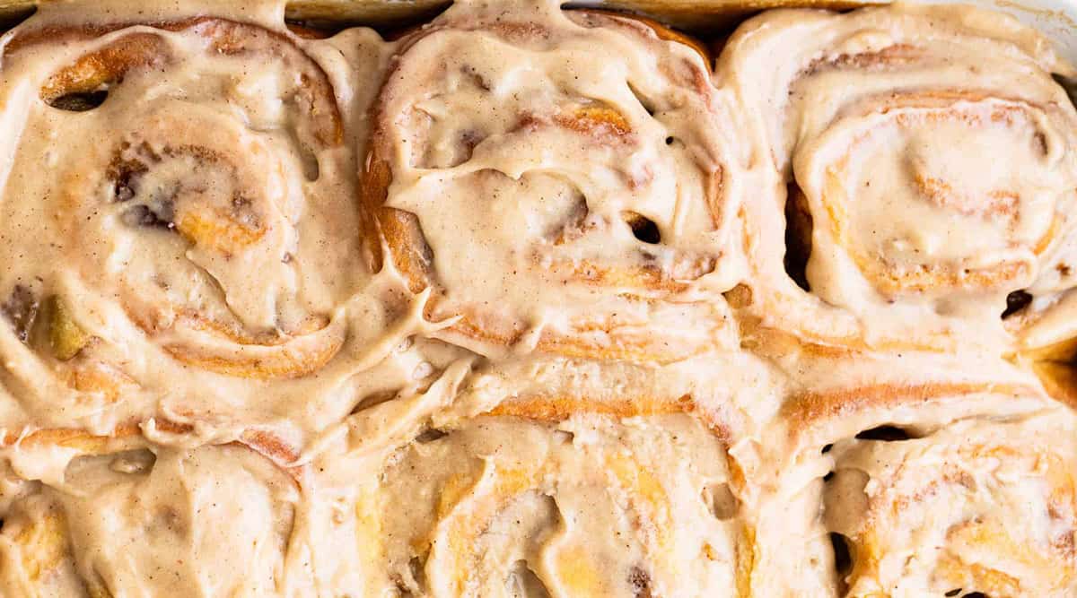 Close-up of freshly baked cinnamon rolls covered in creamy frosting.