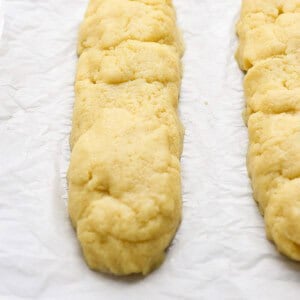 Two unbaked pastry dough logs on parchment paper, placed on a baking sheet.