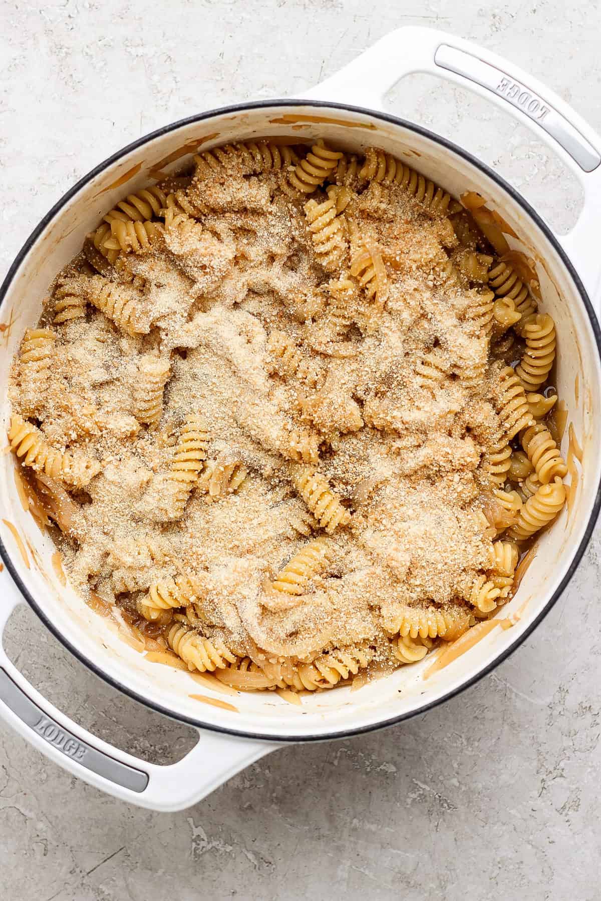 A pot of rotini pasta topped with a layer of grated cheese and breadcrumbs.