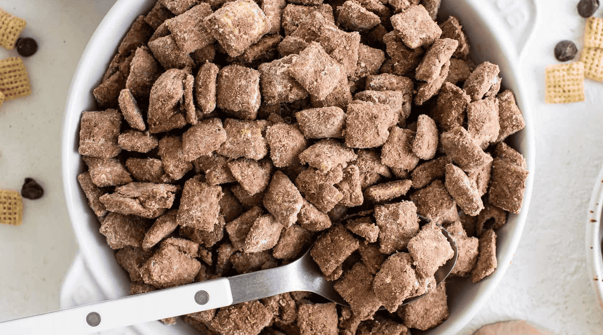 A bowl filled with chocolate-coated cereal pieces, with a serving spoon on the side.