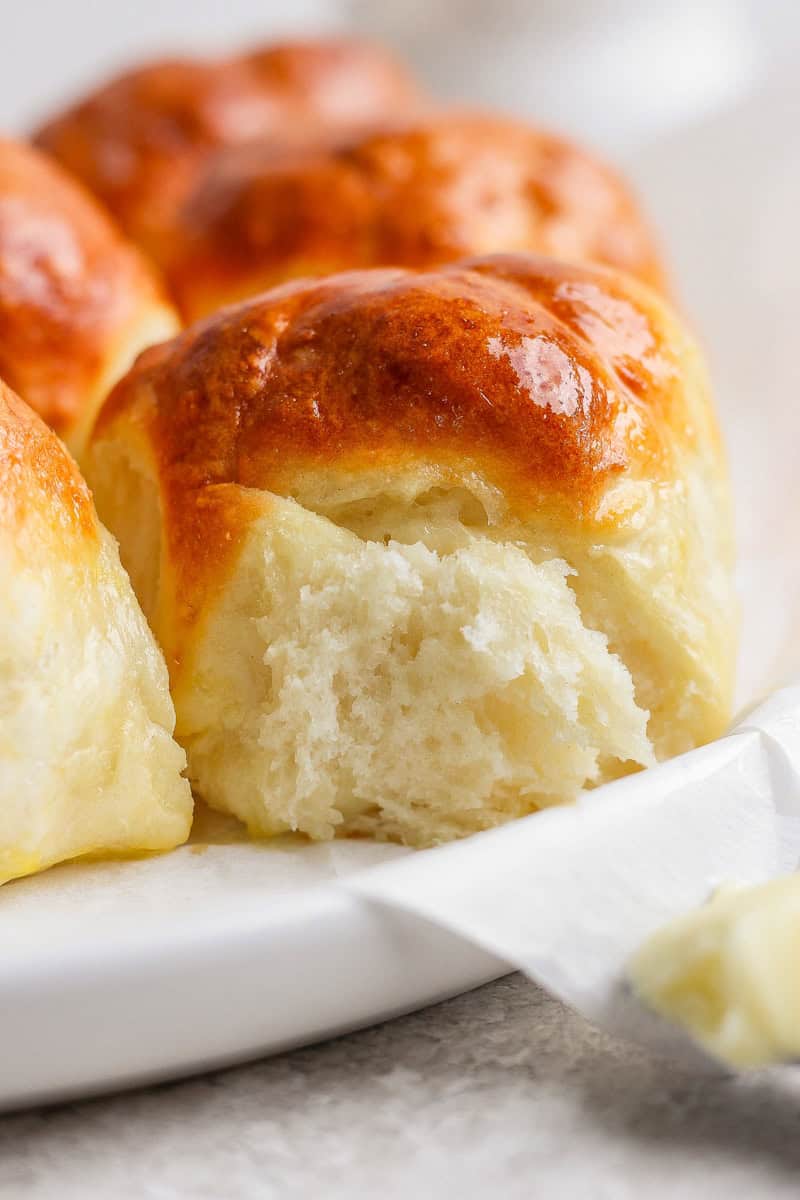 Close-up view of freshly baked, golden brown bread rolls on a white plate.