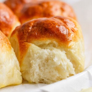 Close-up of freshly baked, golden-brown dinner rolls with a soft, fluffy interior.