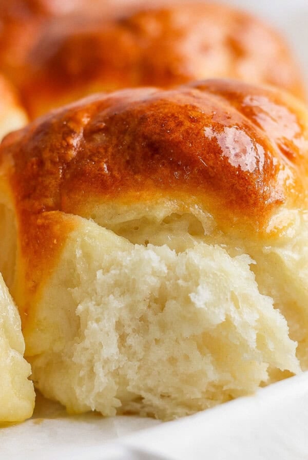 Close-up of freshly baked, golden-brown dinner rolls with a soft, fluffy interior.