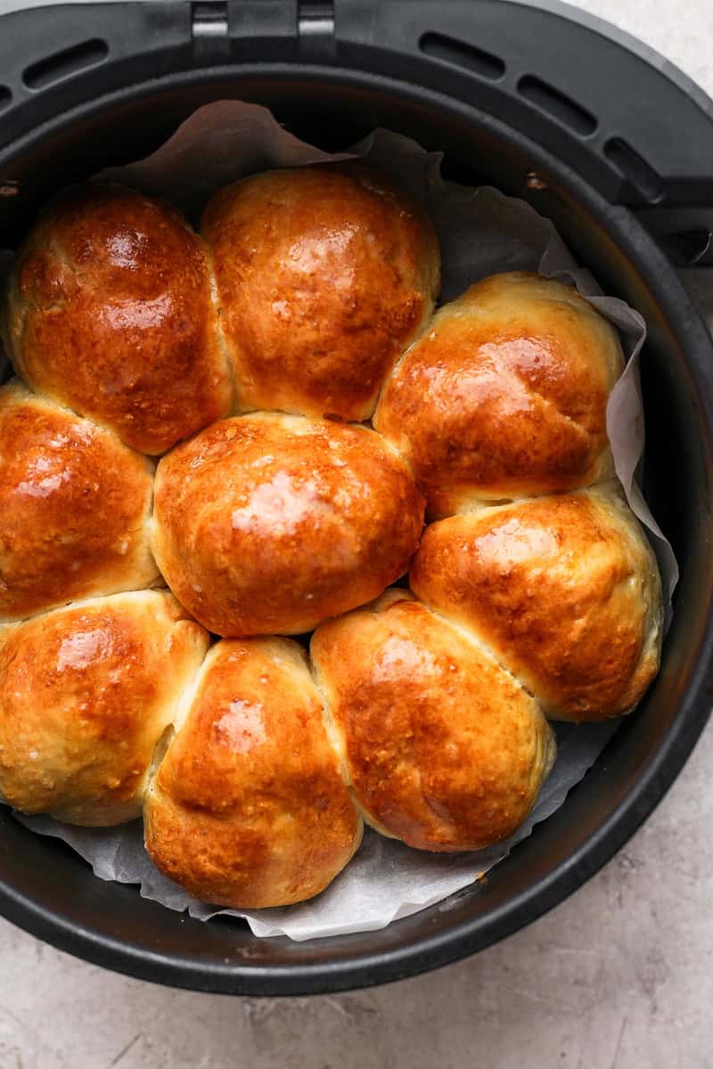 Golden brown rolls arranged in a circular shape inside an air fryer basket, lined with parchment paper.