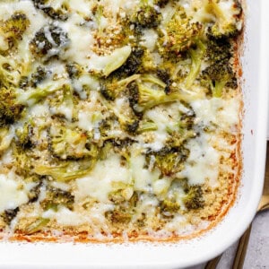 Broccoli and cheese bake in a white rectangular dish, with melted cheese and browned edges.