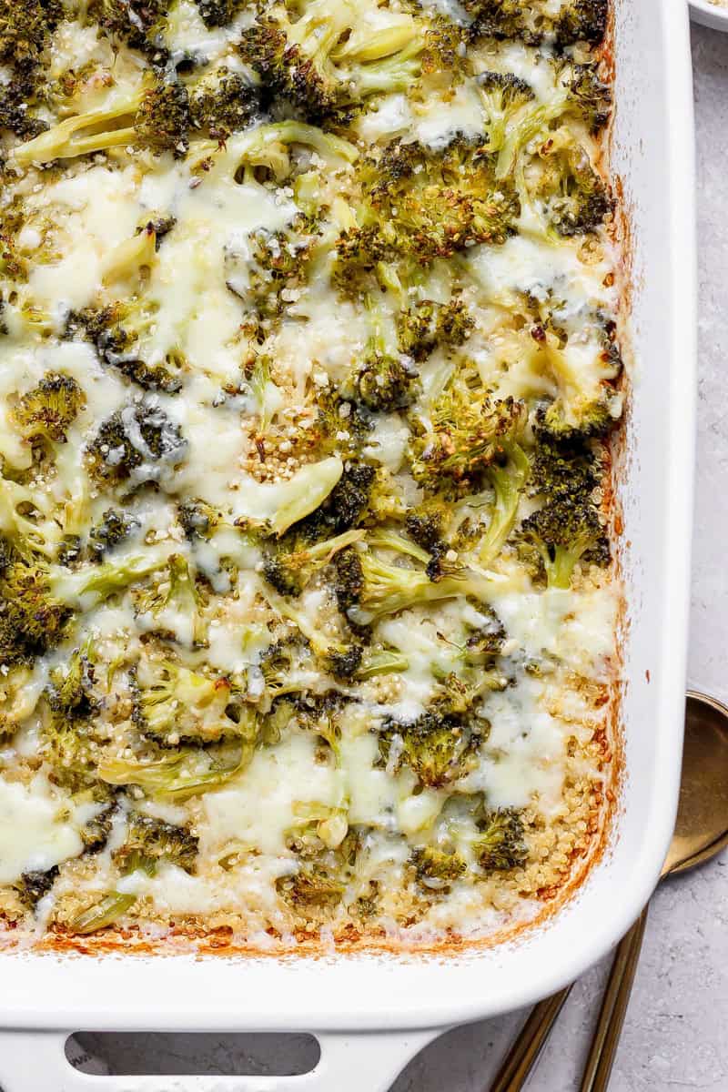 Broccoli casserole topped with melted cheese in a white baking dish.