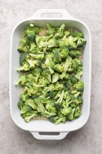 A baking dish filled with raw broccoli florets ready for cooking.