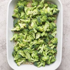 A baking dish filled with raw broccoli florets ready for cooking.