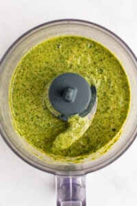 Green sauce in a food processor viewed from above, showing a smooth and evenly blended texture.