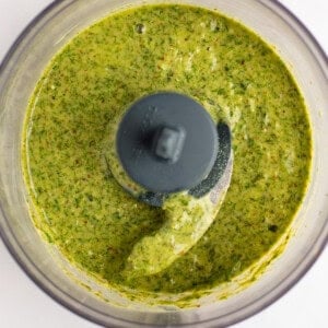 Green sauce in a food processor viewed from above, showing a smooth and evenly blended texture.