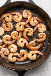 Cooked shrimp seasoned with spices in a black skillet.