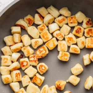 Pan-fried gnocchi, golden brown and arranged in a frying pan.