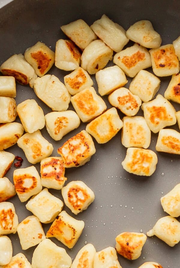 Pan-fried gnocchi, golden brown and arranged in a frying pan.