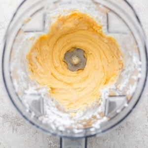 Top view of a blender with creamy, whipped mixture inside, surrounded by a dusting of white powder on the container's edges.