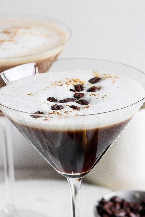 Two classic espresso martinis served in chic martini glasses, each boasting a frothy top and perfectly placed coffee bean garnish.