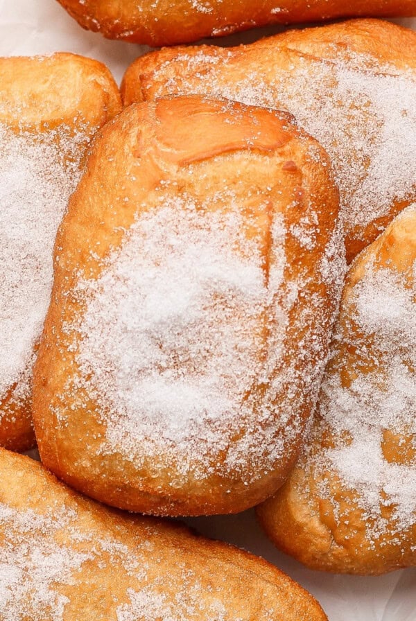 A pile of sugared beignets on a white surface.