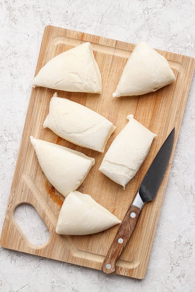 Sliced triangles of dough are arranged on a wooden cutting board with a knife.