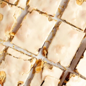 Rectangular pastries covered with a light beige icing are arranged in a 3x4 grid on a sheet of parchment paper.