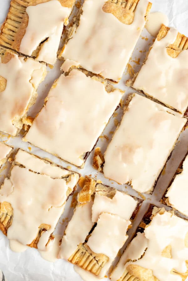 Rectangular pastries covered with a light beige icing are arranged in a 3x4 grid on a sheet of parchment paper.