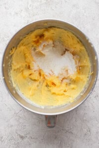Mixing bowl with creamed butter and sugar on a textured surface.