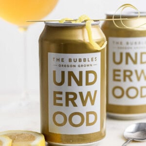 A can of Underwood The Bubbles wine from Oregon, transformed into a refreshing canned champagne cocktail, garnished with a lemon twist on a skewer.