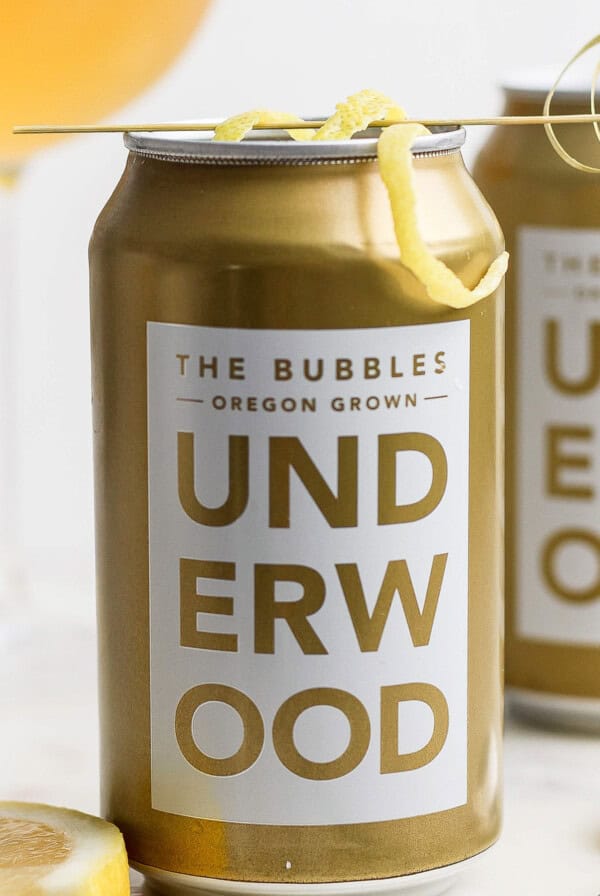 A can of Underwood The Bubbles wine from Oregon, transformed into a refreshing canned champagne cocktail, garnished with a lemon twist on a skewer.