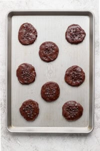 Unbaked chocolate cookies arranged on a baking sheet, topped with chocolate chips.