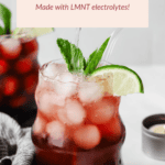 A glass of Sleepy Girl Mocktail with ice, mint garnish, and lime slices. Label reads: "Made with LMNT electrolytes." Another similar drink is in the background.