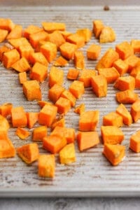 Chopped sweet potato pieces spread out on a baking tray.