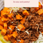 A bowl of sloppy joe mix with ground beef, diced sweet potatoes, and toppings including pickles, shredded cheese, and red onions.