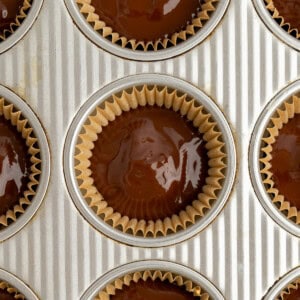 Muffin tin filled with cupcake liners containing chocolate batter.