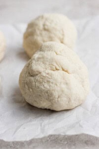 Close-up of two balls of dough on parchment paper, ready for baking.