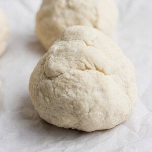 Close-up of two balls of dough on parchment paper, ready for baking.