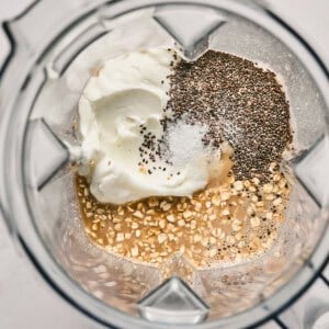 Ingredients in a blender: yogurt, chia seeds, salt, oats, and a liquid.
