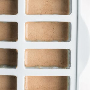 Ice tray filled with light brown liquid, viewed from the top.