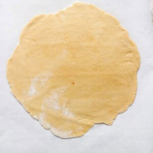 Rolled-out pie dough on parchment paper, ready for filling and baking.