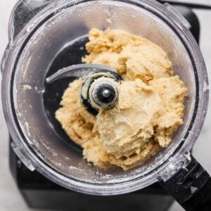 Food processor containing beige cookie dough mixture.