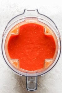 Top view of a blender containing smooth red tomato sauce on a light surface, reminiscent of the perfect partner to grilled cheese.