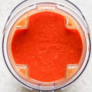 Top view of a blender containing smooth red tomato sauce on a light surface, reminiscent of the perfect partner to grilled cheese.