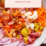 Bowl of Italian chop salad with sliced onions, cherry tomatoes, carrots, chickpeas, olives, salami, and feta. Text above reads, "No-lettuce Italian Chop Salad - Healthy lunch recipe!.