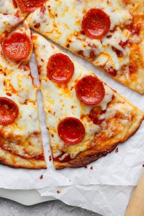 Slices of pepperoni pizza with melted cheese on parchment paper.