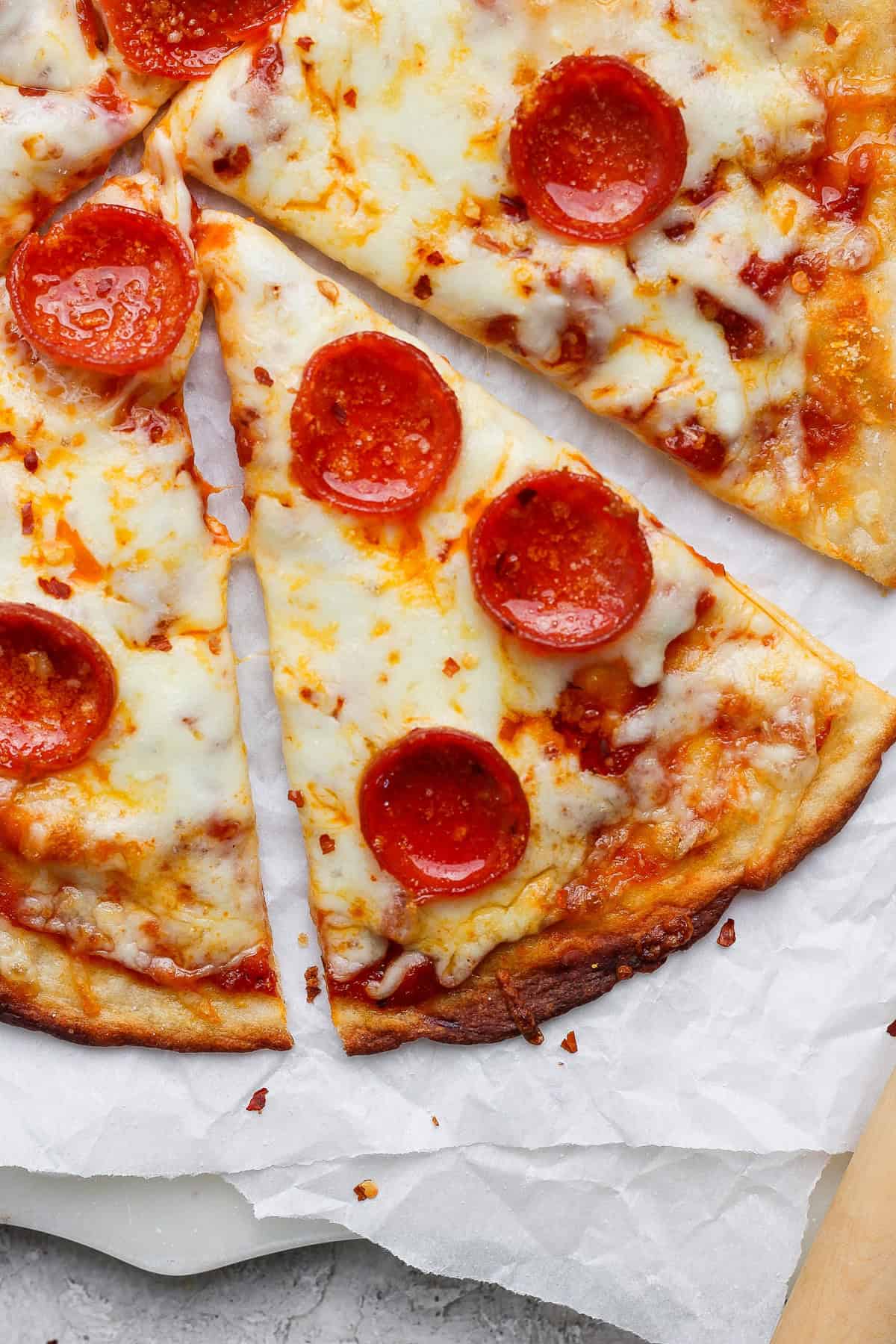 Slices of pepperoni pizza with melted cheese on parchment paper.