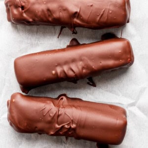 Five chocolate-coated bars arranged in a row on parchment paper.