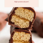 Two stacked halves of a peanut butter protein Twix bar, showing a layered interior coated with chocolate. Text above describes it as a high-protein dessert.